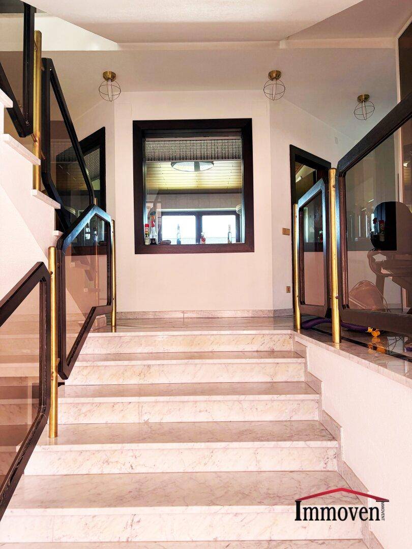 Elegante Marmortreppe mit modernem Geländer und Fenster auf halber Höhe.
