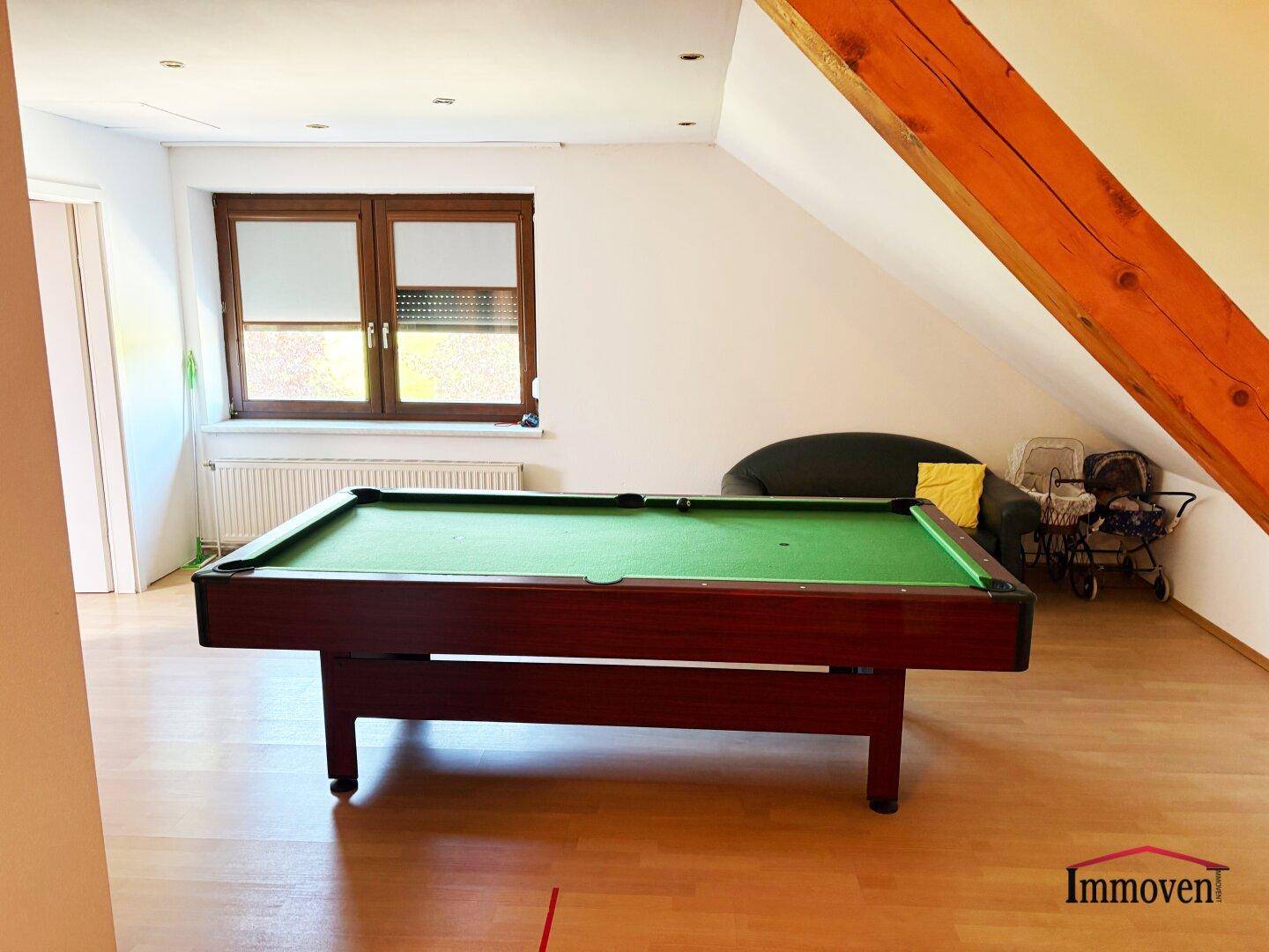 Dachgeschoss-Spielzimmer mit Billardtisch, schräger Decke und sichtbaren Holzbalken.