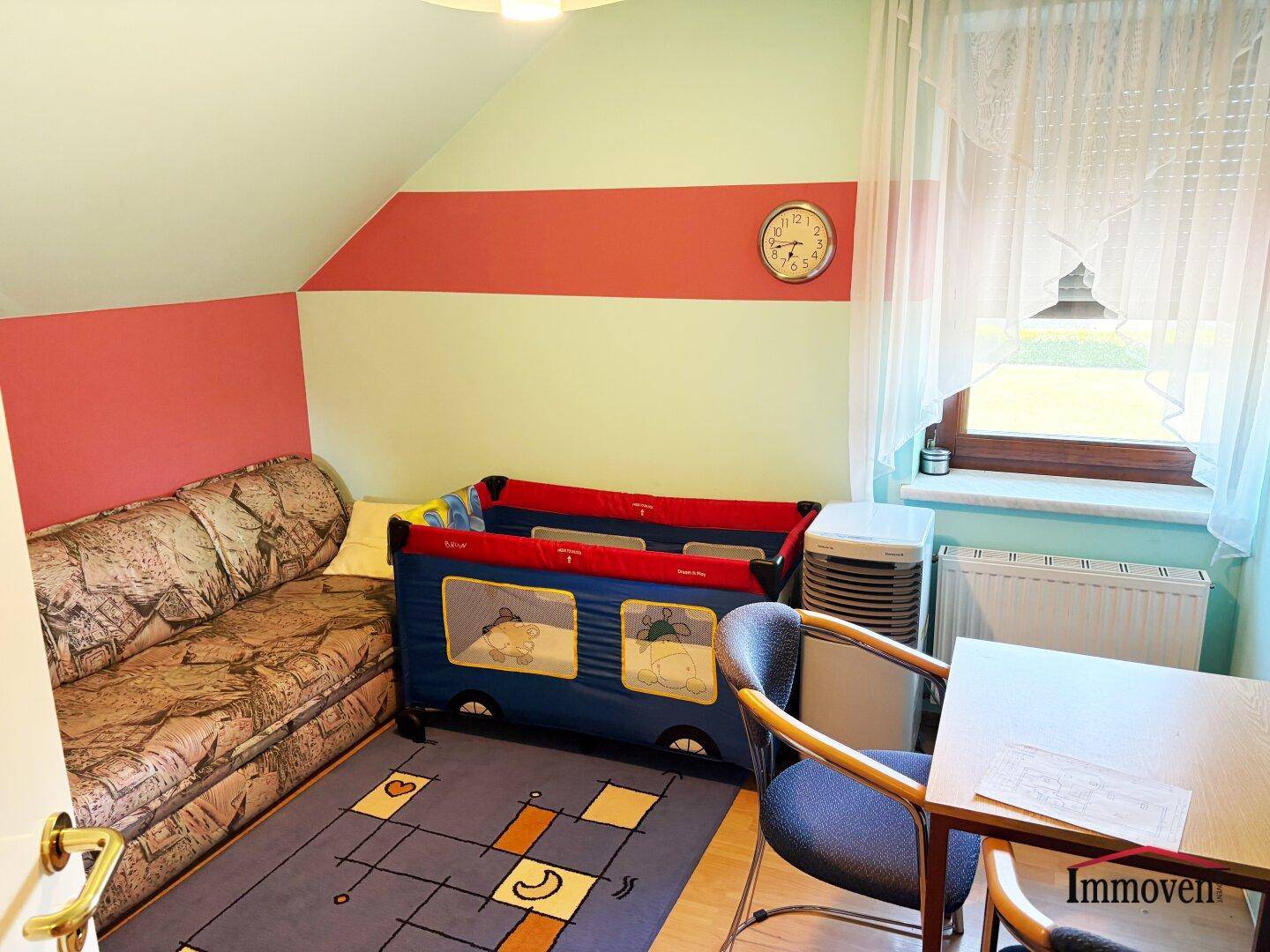 Kleines Kinderzimmer im Dachgeschoss mit farbenfrohen Wänden, Babybett und Fenster.