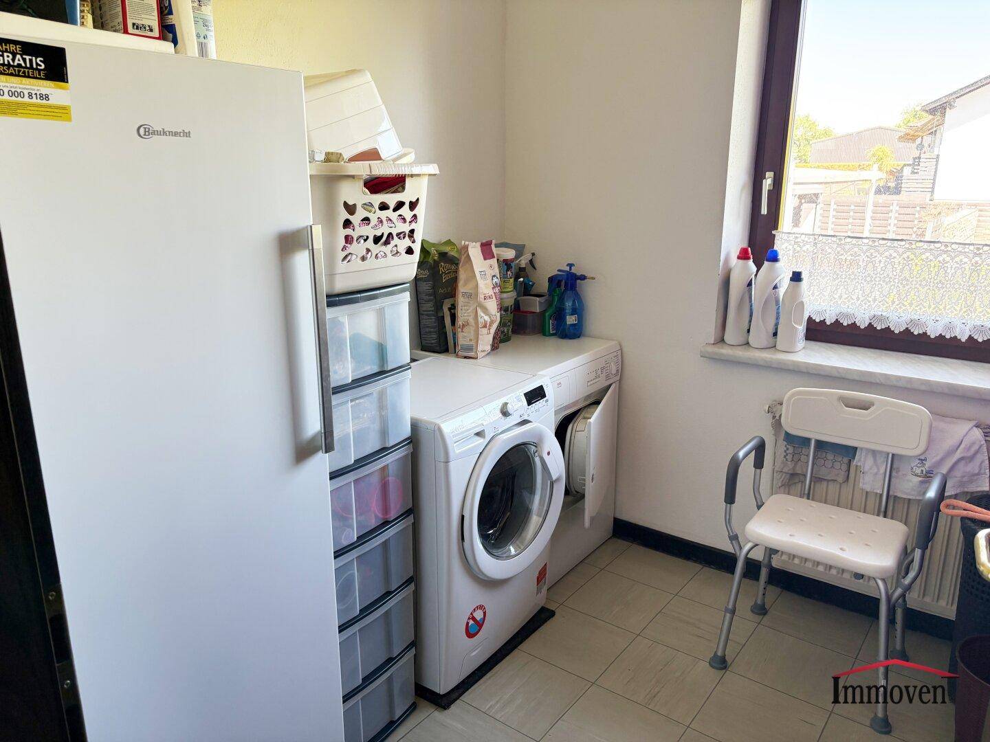 Hauswirtschaftsraum mit Waschmaschine, Trockner, Kühlschrank und Fenster für natürliche Belüftung.