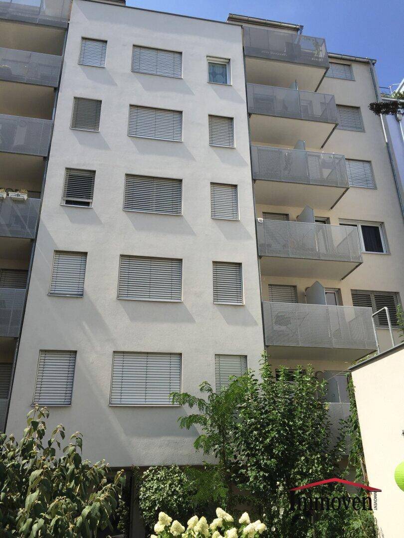 Moderne Gebäudefassade mit zahlreichen Balkonen und Fenstern, ausgestattet mit Jalousien.