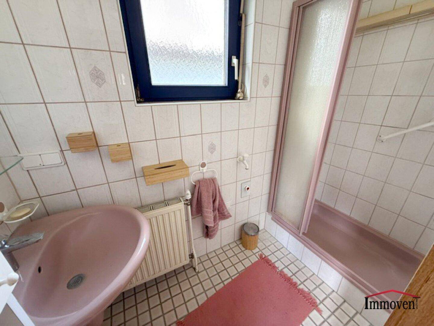 Badezimmer im Stil der 80er Jahre mit rosa Waschbecken, Duschkabine und Fliesen.