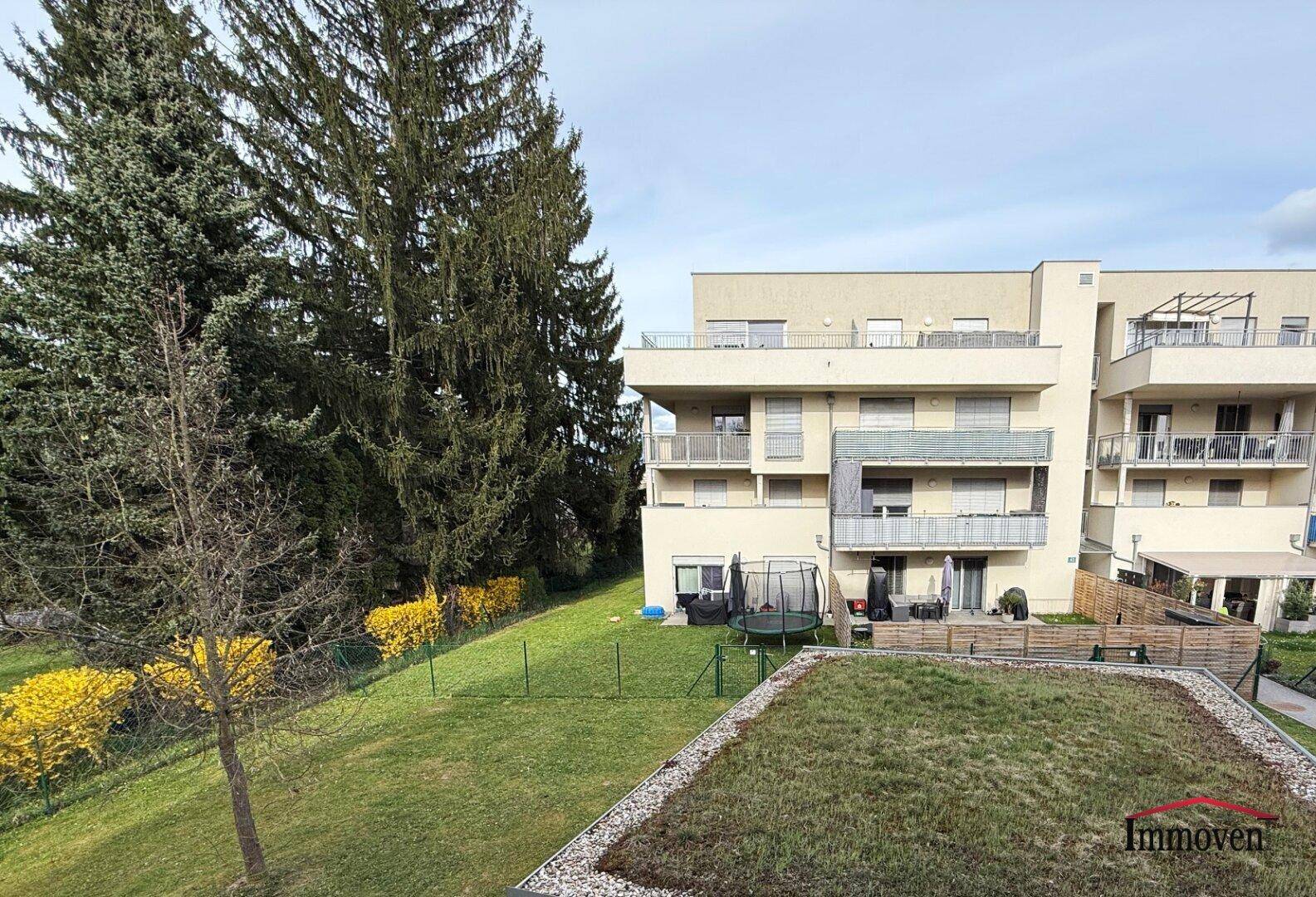 Blick von oben auf eine Grünfläche mit Trampolin und angrenzende Wohngebäude.