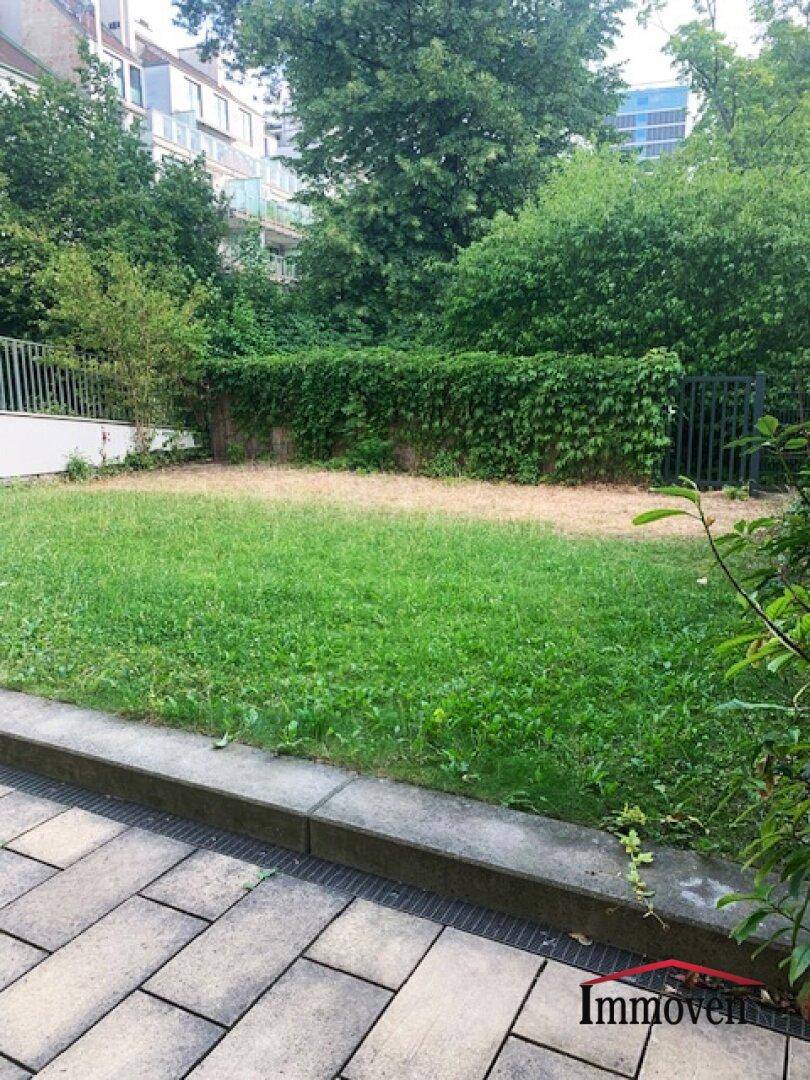 Gepflegte Rasenfläche im Garten, umgeben von üppigem Grün und einer schützenden Hecke.
