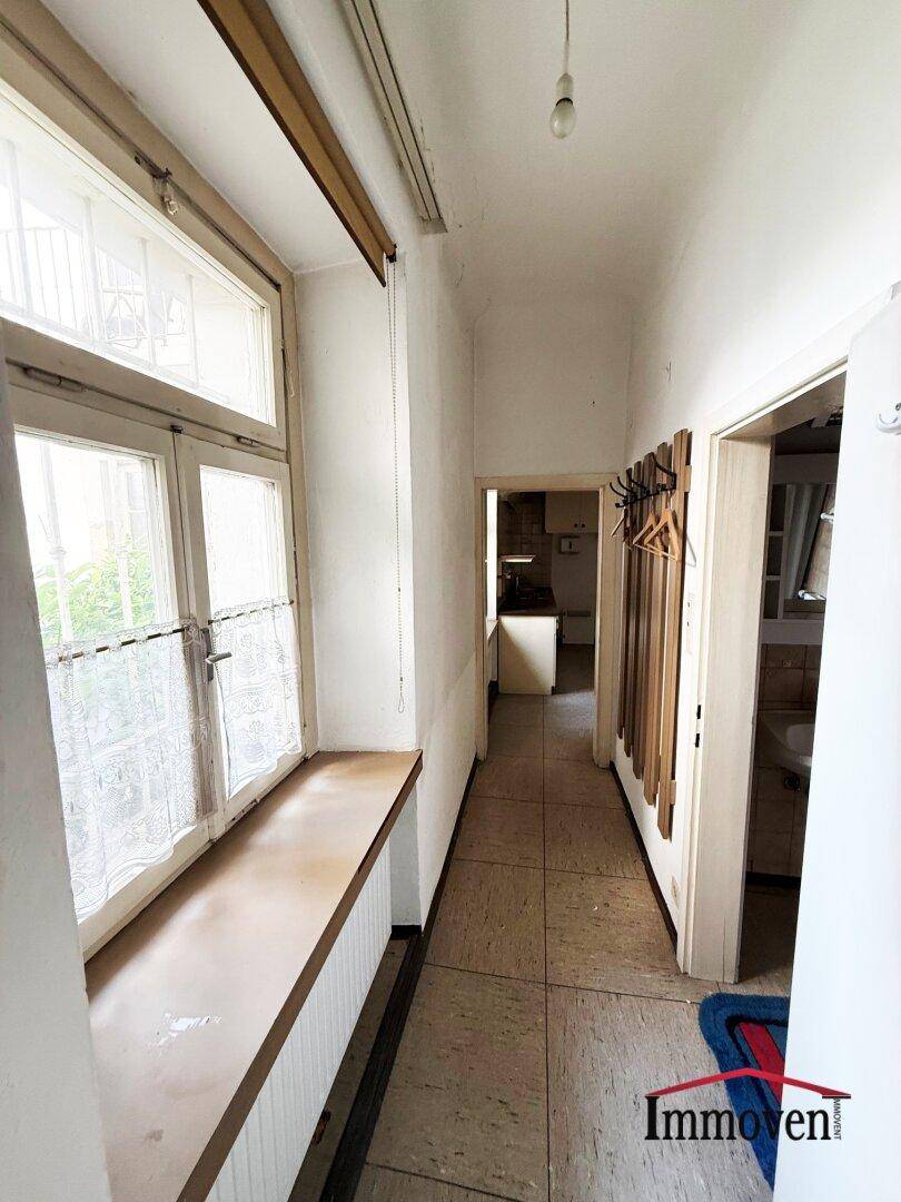 Langer Flur mit Fliesenboden und einem großen Fenster, das den Bereich mit natürlichem Licht versorgt.