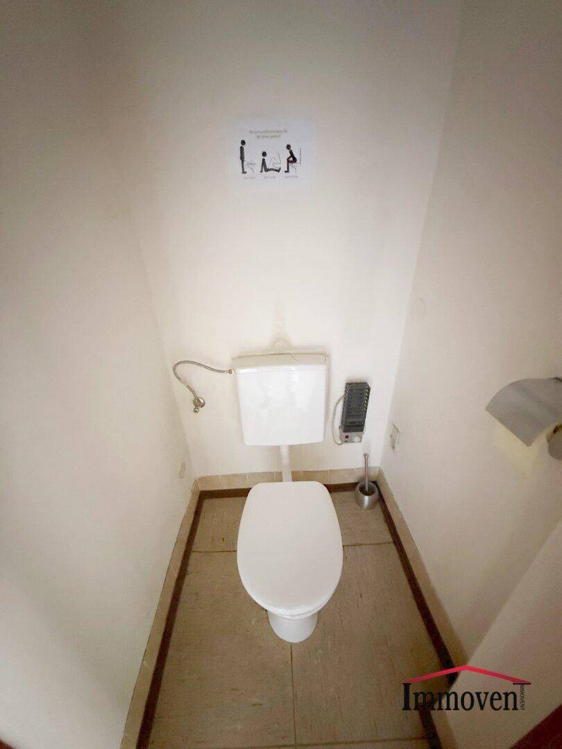 Separate Toilette mit WC und Fliesenboden, in einem einfachen, aber funktionalen Zustand.