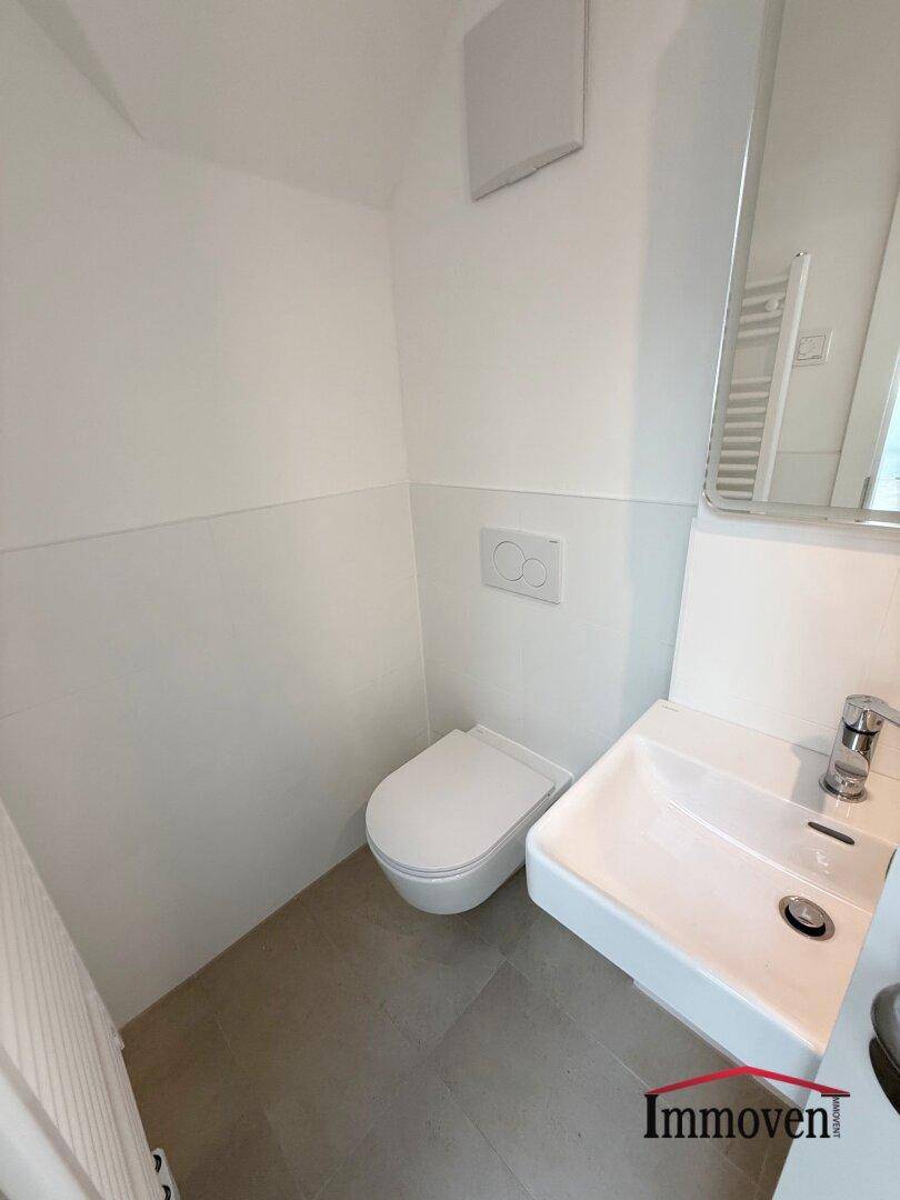 Separates Gäste-WC mit wandhängender Toilette und kleinem Waschbecken.