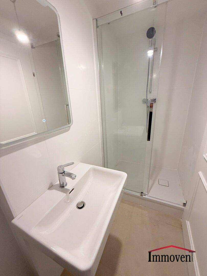 Modernes Badezimmer mit Dusche, Einzelwaschbecken und weiß gefliesten Wänden.