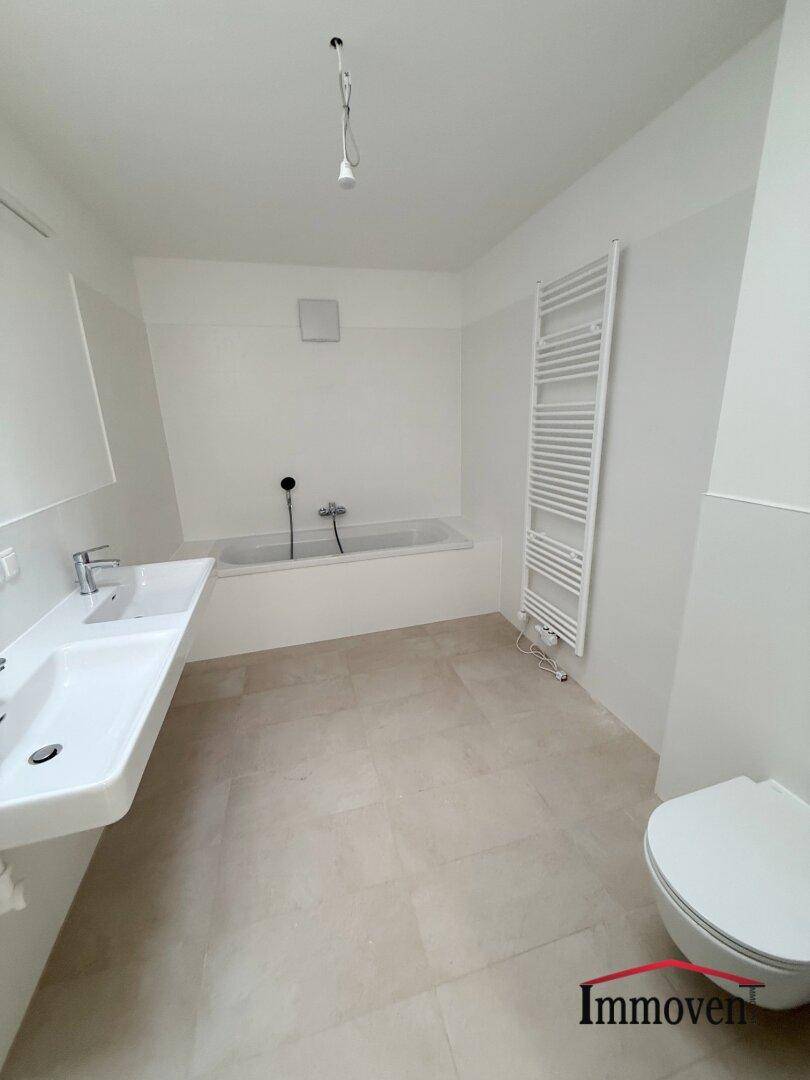 Geräumiges Badezimmer mit Badewanne, Doppelwaschbecken und beheiztem Handtuchhalter.