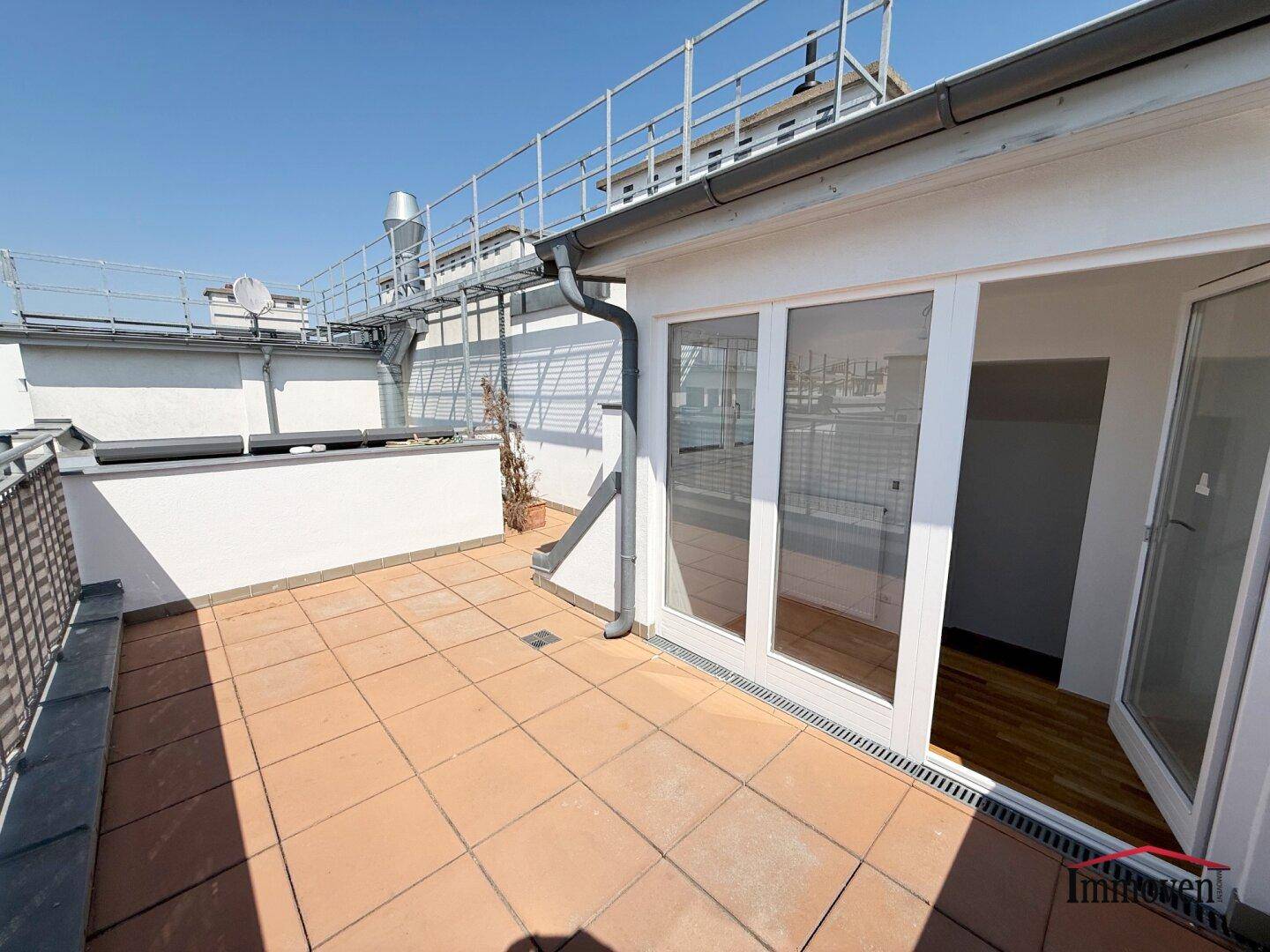Geräumige Dachterrasse mit Fliesenboden und Zugang zu den Innenräumen.