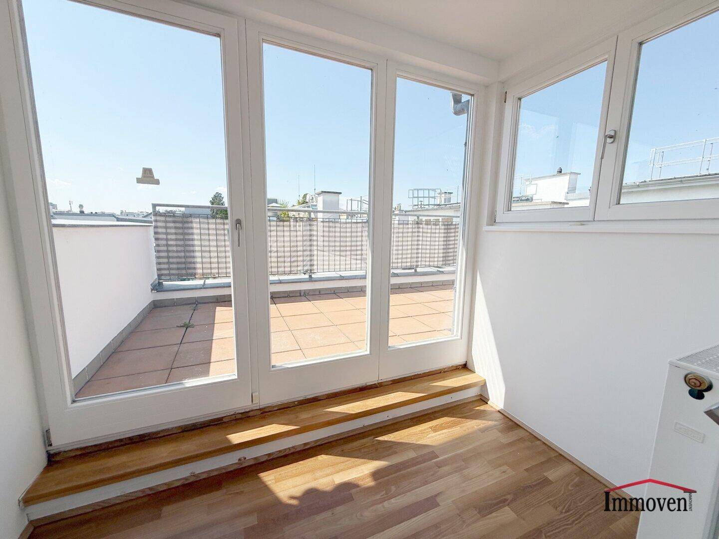 Heller Wintergarten mit Zugang zur Dachterrasse und weitem Blick über die Stadt.