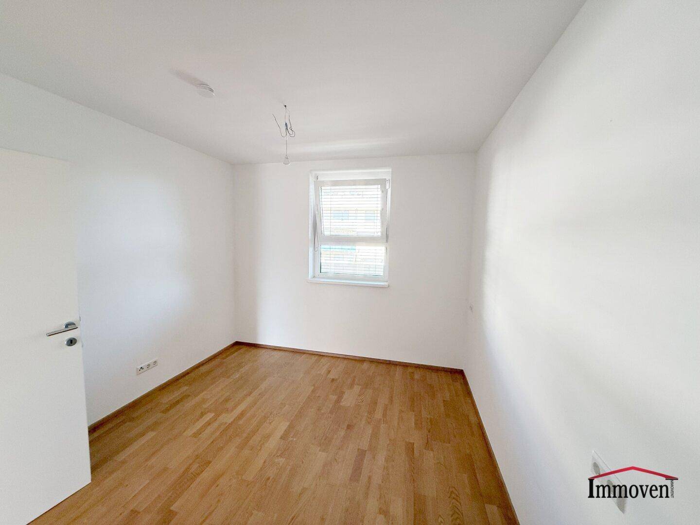 Ruhiges Zimmer mit Parkettboden und einem Fenster, das viel Tageslicht hereinlässt.