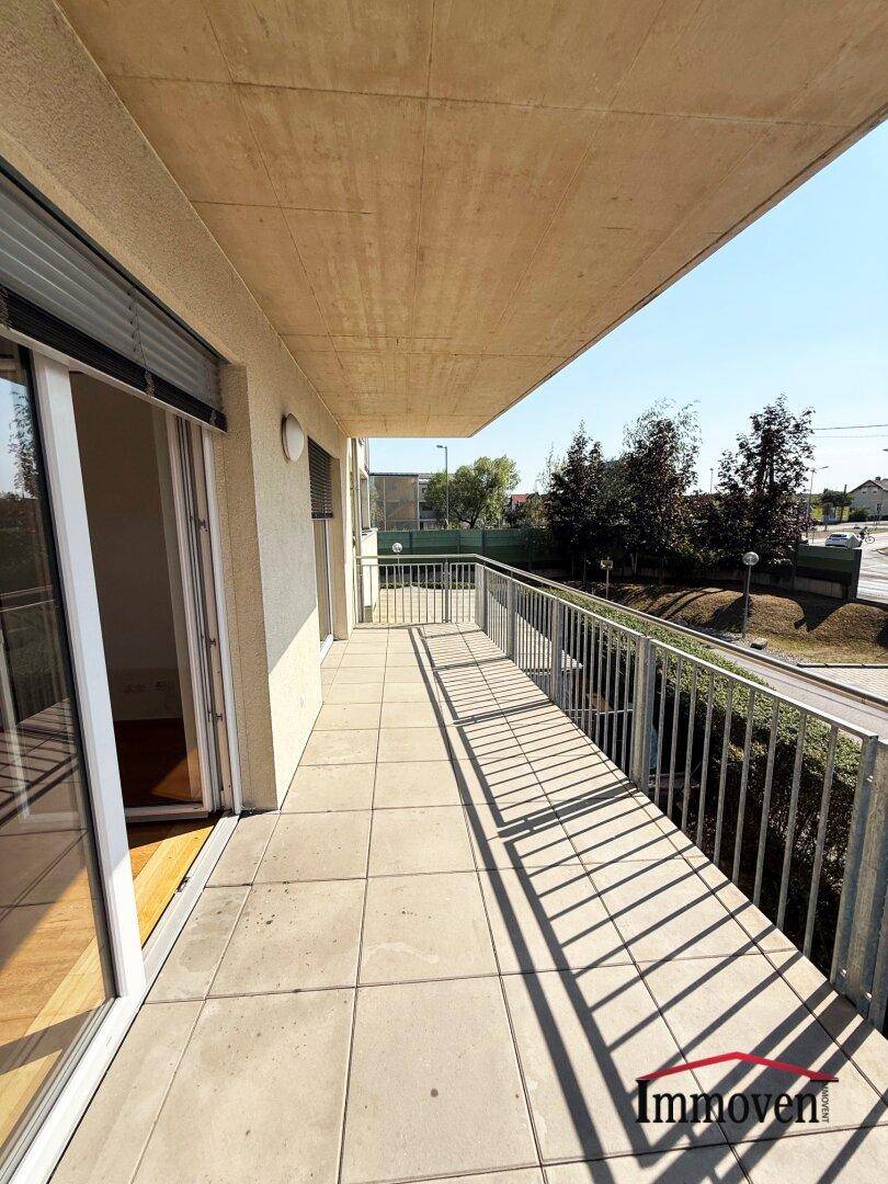 Geräumiger Balkon mit Fliesenboden und Metallgeländer, bietet einen Blick auf die Umgebung.