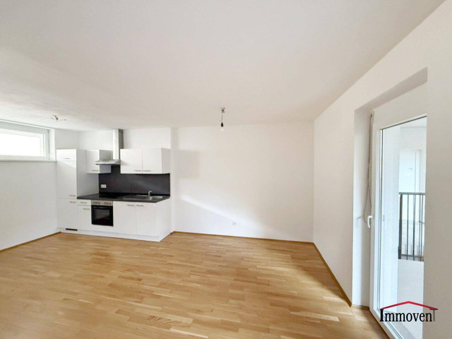 Offene Küche mit weißen Schränken und Parkettboden, bereit für die Einrichtung des Wohnbereichs.