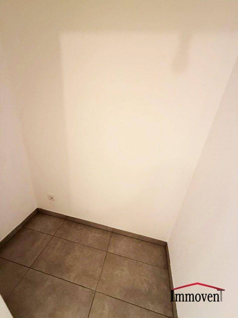Kleiner, leerer Abstellraum mit hellen Wänden und dunklen Bodenfliesen, ideal für Lagerung.