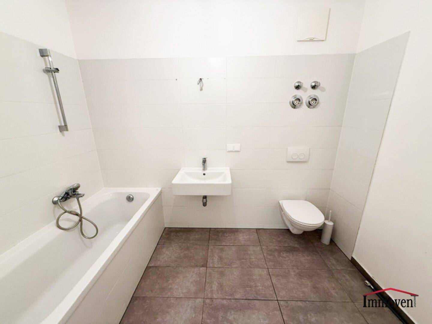 Modernes Badezimmer mit weißen Fliesen, Badewanne, wandhängendem WC und Einzelwaschbecken.