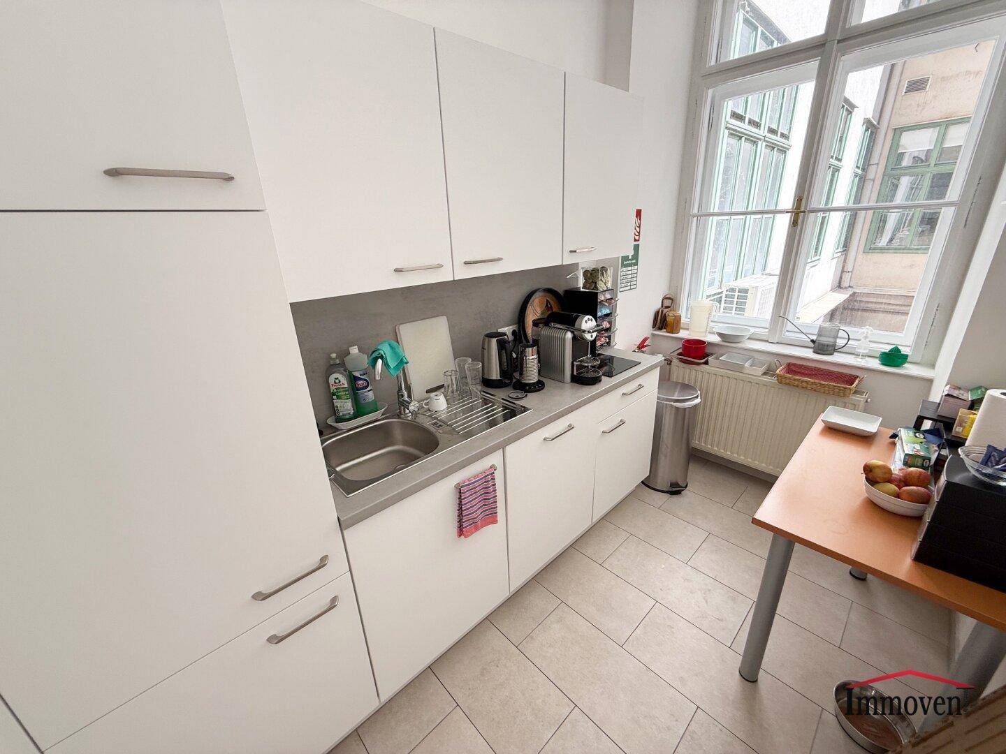 Funktionale Küchenzeile mit weißen Schränken, Spüle und Kaffeemaschine, ideal für Pausen.