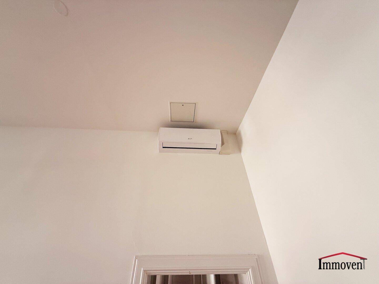 Detailaufnahme einer Klimaanlage an der Wand in einem hellen Innenraum.