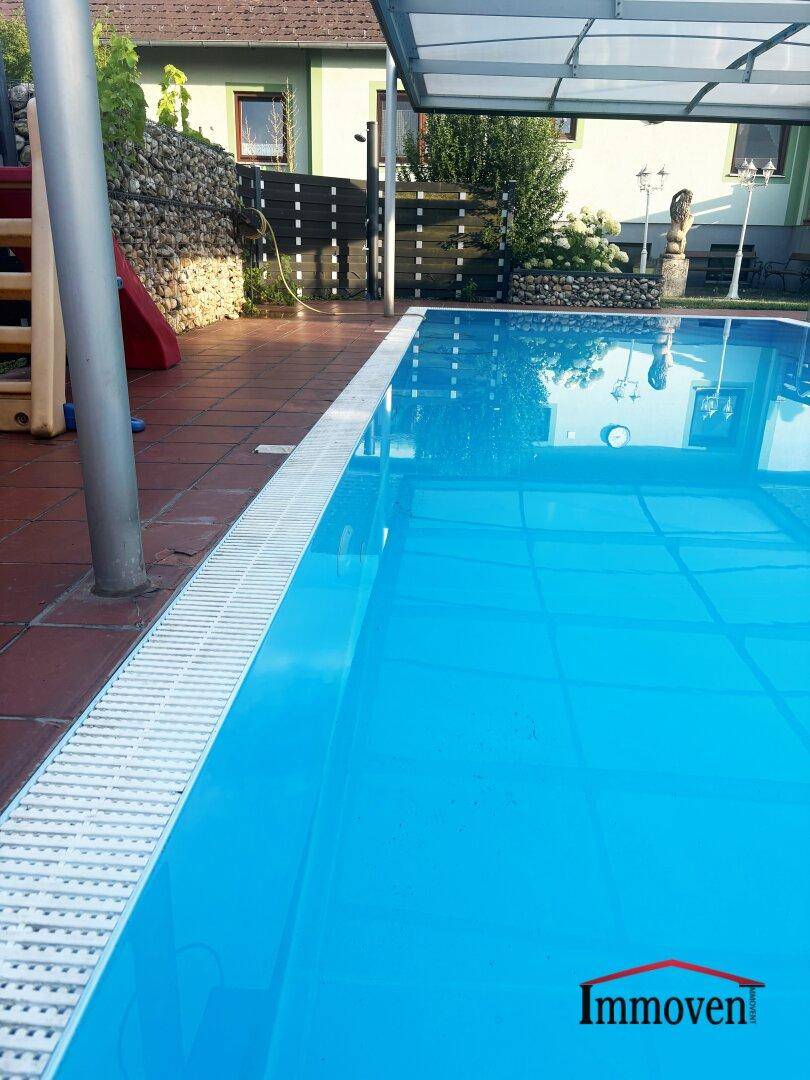 Nahaufnahme eines blauen Swimmingpools mit gefliestem Rand und klarem Wasser an einem sonnigen Tag.