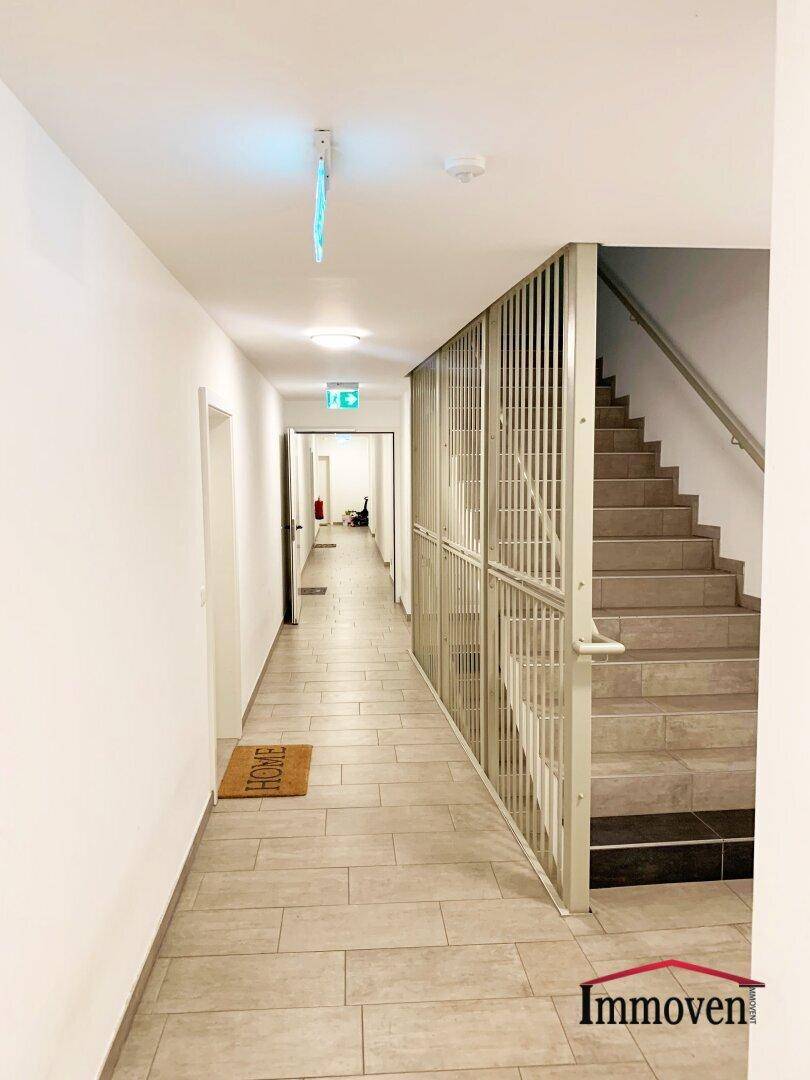 Heller Flur mit Fliesenboden und Zugang zu einer Treppe.