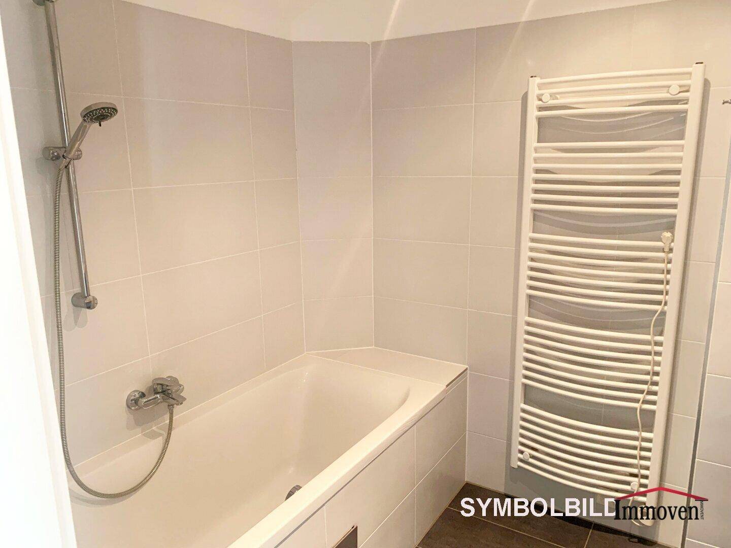 Modernes Badezimmer mit Badewanne, Duschfunktion und beheiztem Handtuchhalter.
