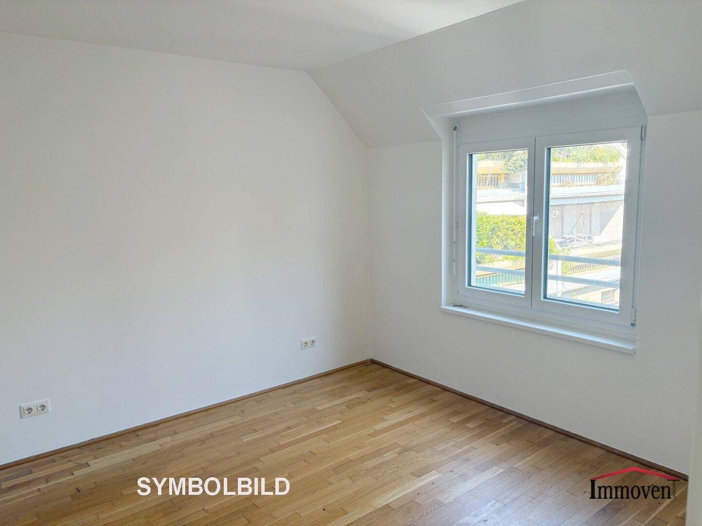 Leeres Zimmer mit Parkettboden, weißen Wänden und Fenster mit Blick ins Grüne.