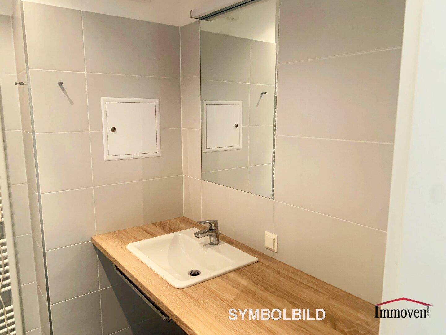 Badezimmer mit Einzelwaschbecken, Holzwaschtisch und großem Spiegel.