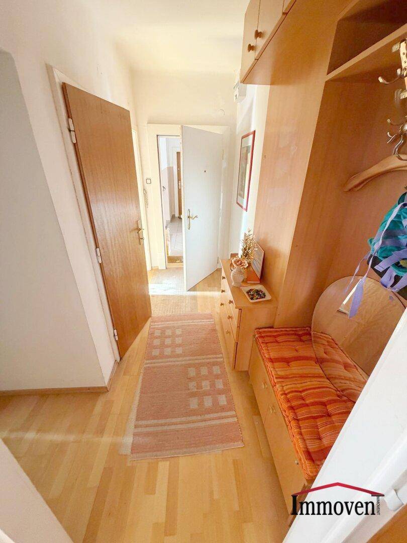 Eingangsbereich mit Garderobe, Sitzbank und Holzmöbeln, bietet praktischen Stauraum und eine einladende Atmosphäre.