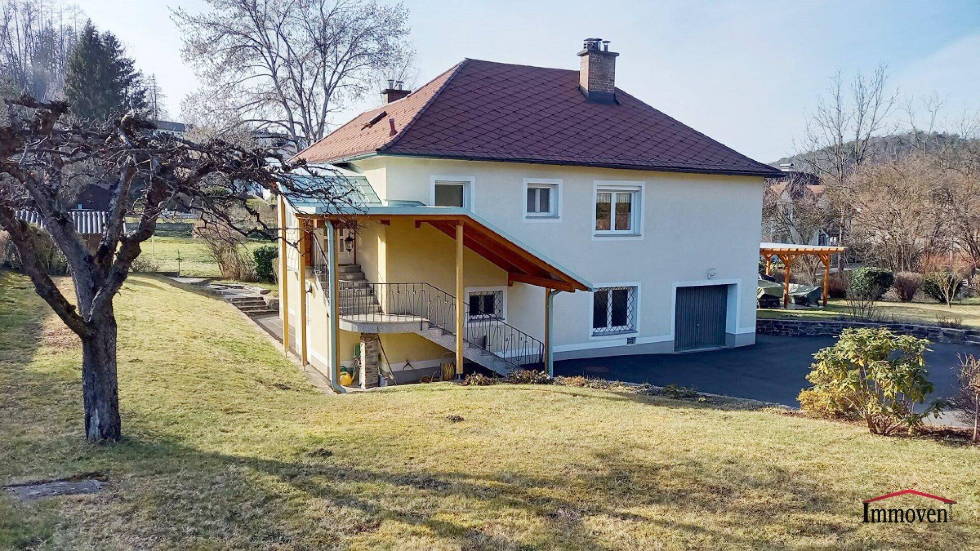 Einfamilienhaus mit Satteldach, integrierter Garage und großem Gartenbereich in ländlicher Umgebung.
