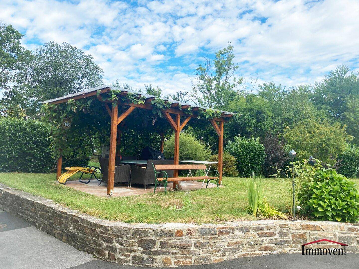 Großer Garten mit begrünter Holzpergola und gemütlicher Sitzecke für entspannte Stunden.