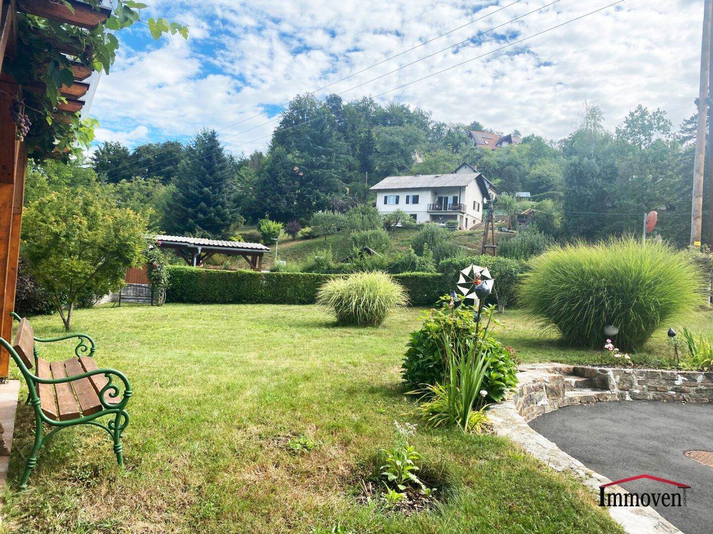 Weitläufiger Garten mit Rasenfläche, Ziersträuchern und Blick auf die umliegende Landschaft.