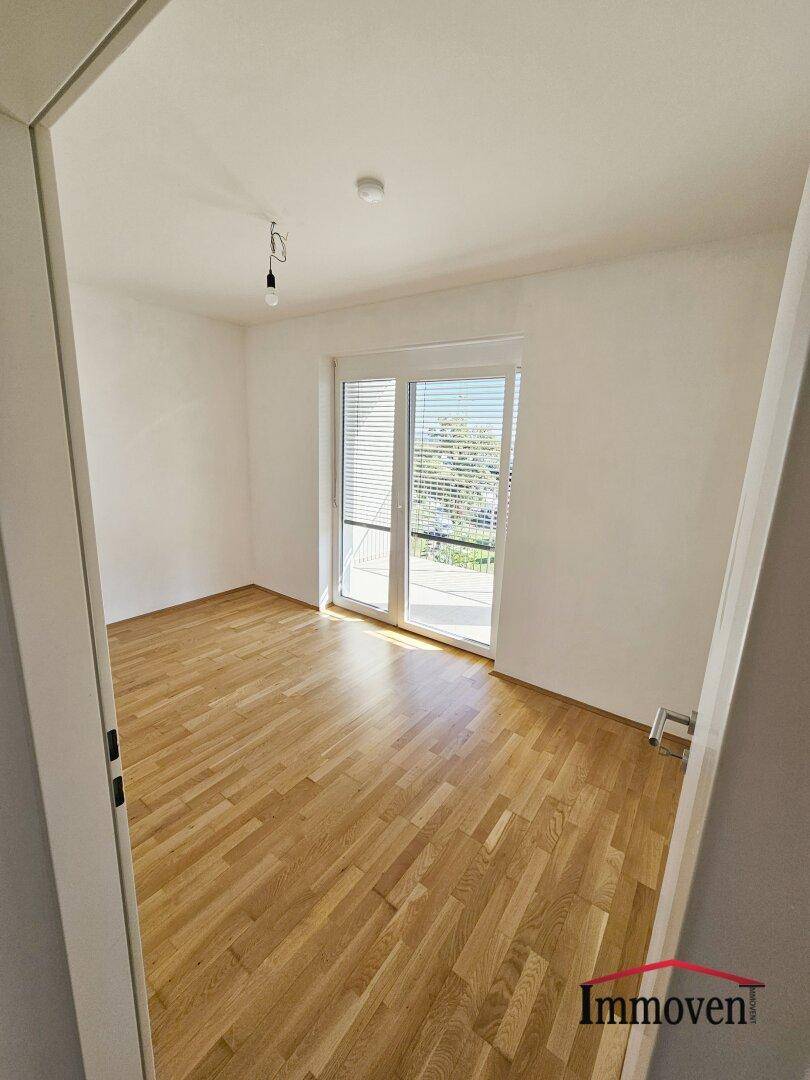 Geräumiges Schlafzimmer mit Parkettboden und direktem Zugang zu einem privaten Balkon.