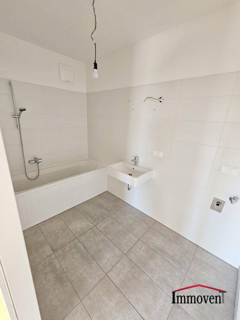 Modernes Badezimmer mit Badewanne, Dusche und einem einzelnen Waschbecken, hell gefliest.