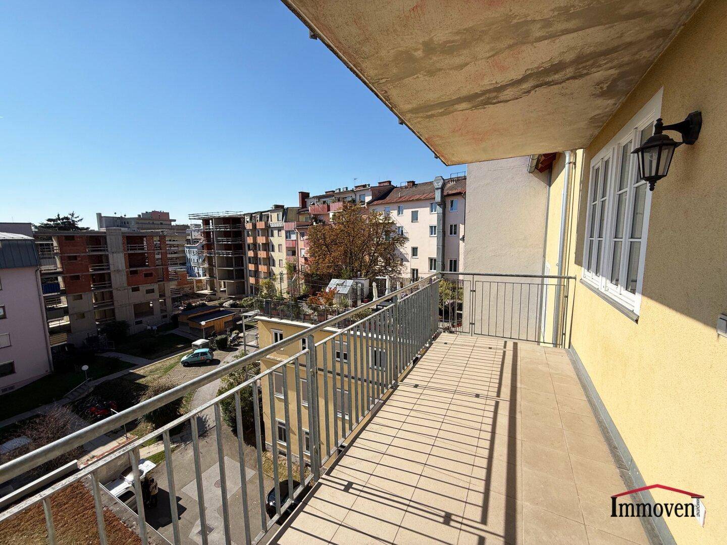 Langer Balkon mit Fliesenboden und Blick auf die umliegende Bebauung.