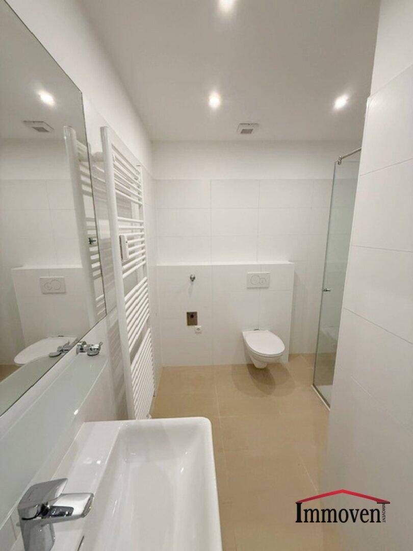 Modernes Badezimmer mit Dusche, Toilette, Waschbecken und beheiztem Handtuchhalter.
