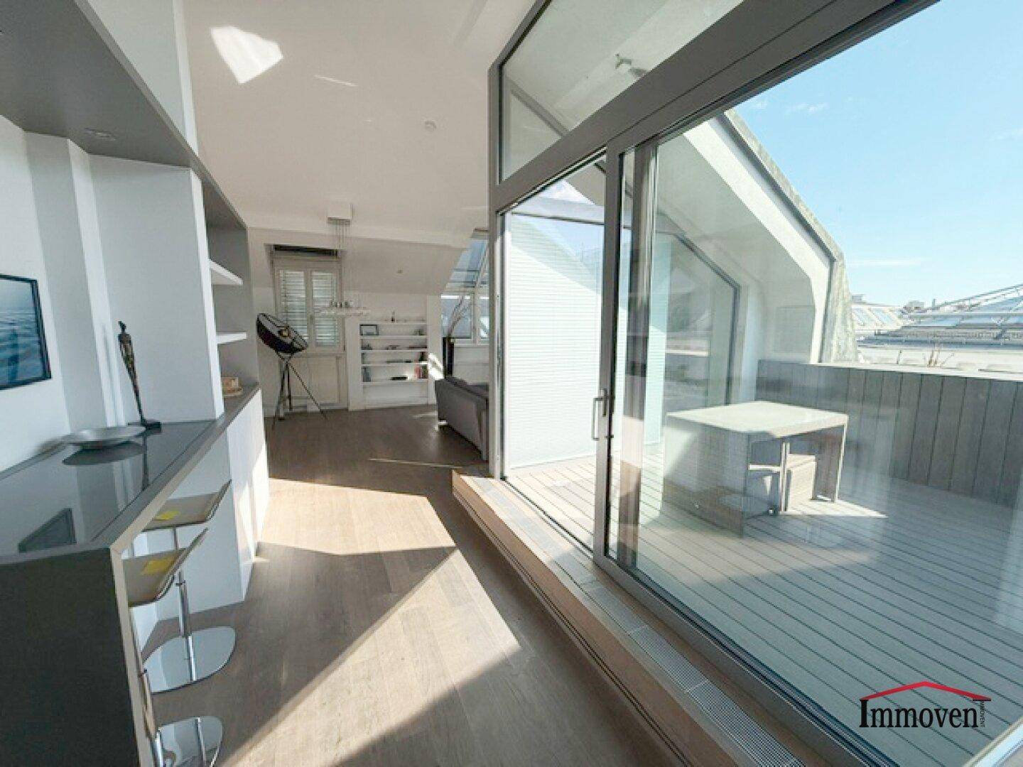 Offener Wohnbereich mit moderner Bar und direktem Zugang zur sonnigen Dachterrasse.