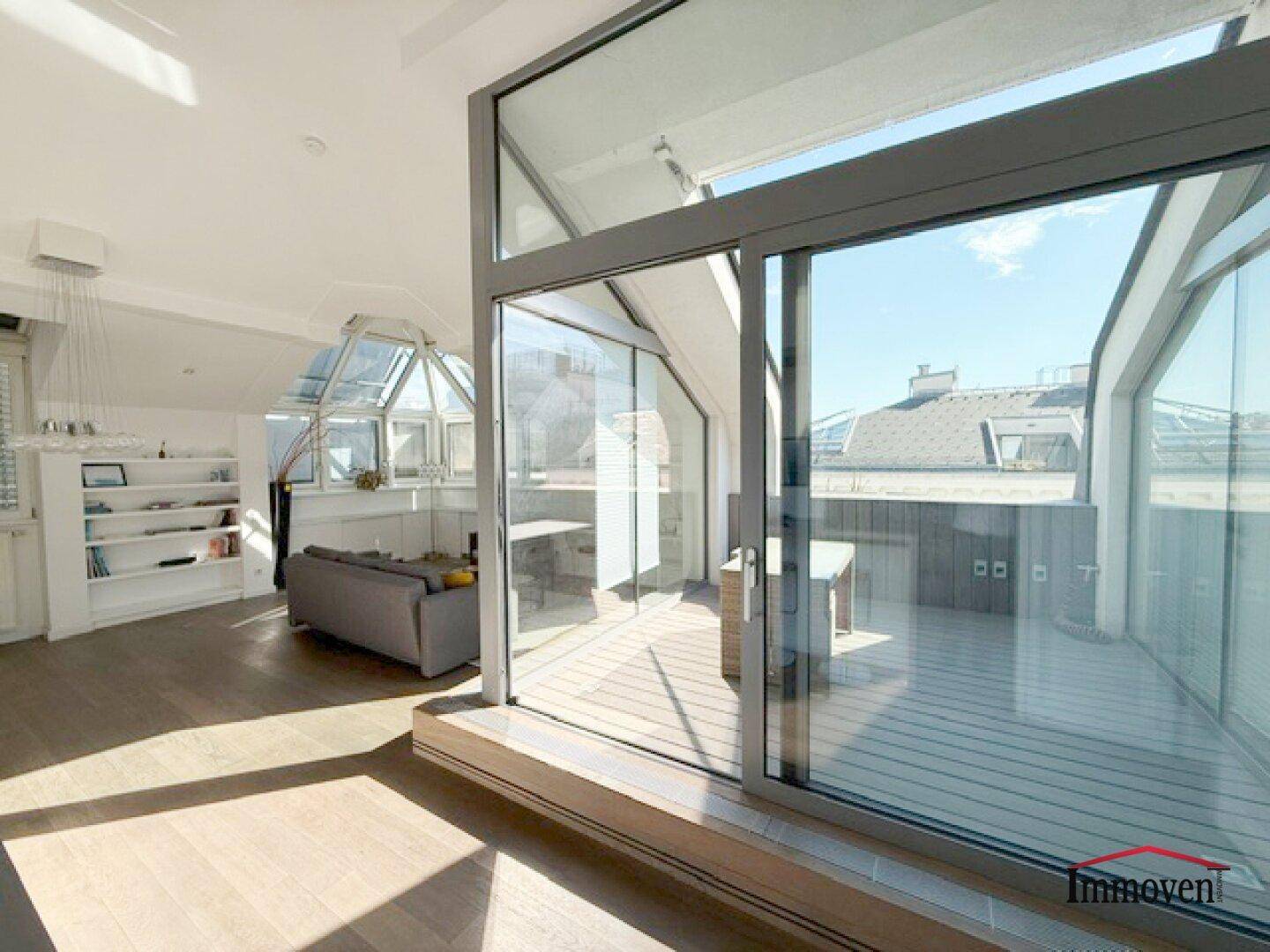 Helles Wohnzimmer mit Holzboden und Zugang zu einer sonnigen Dachterrasse.