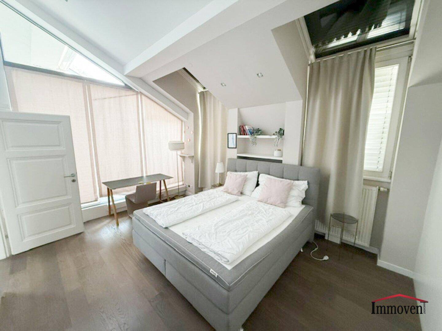 Helles Schlafzimmer mit Holzboden, Doppelbett und Dachfenstern.