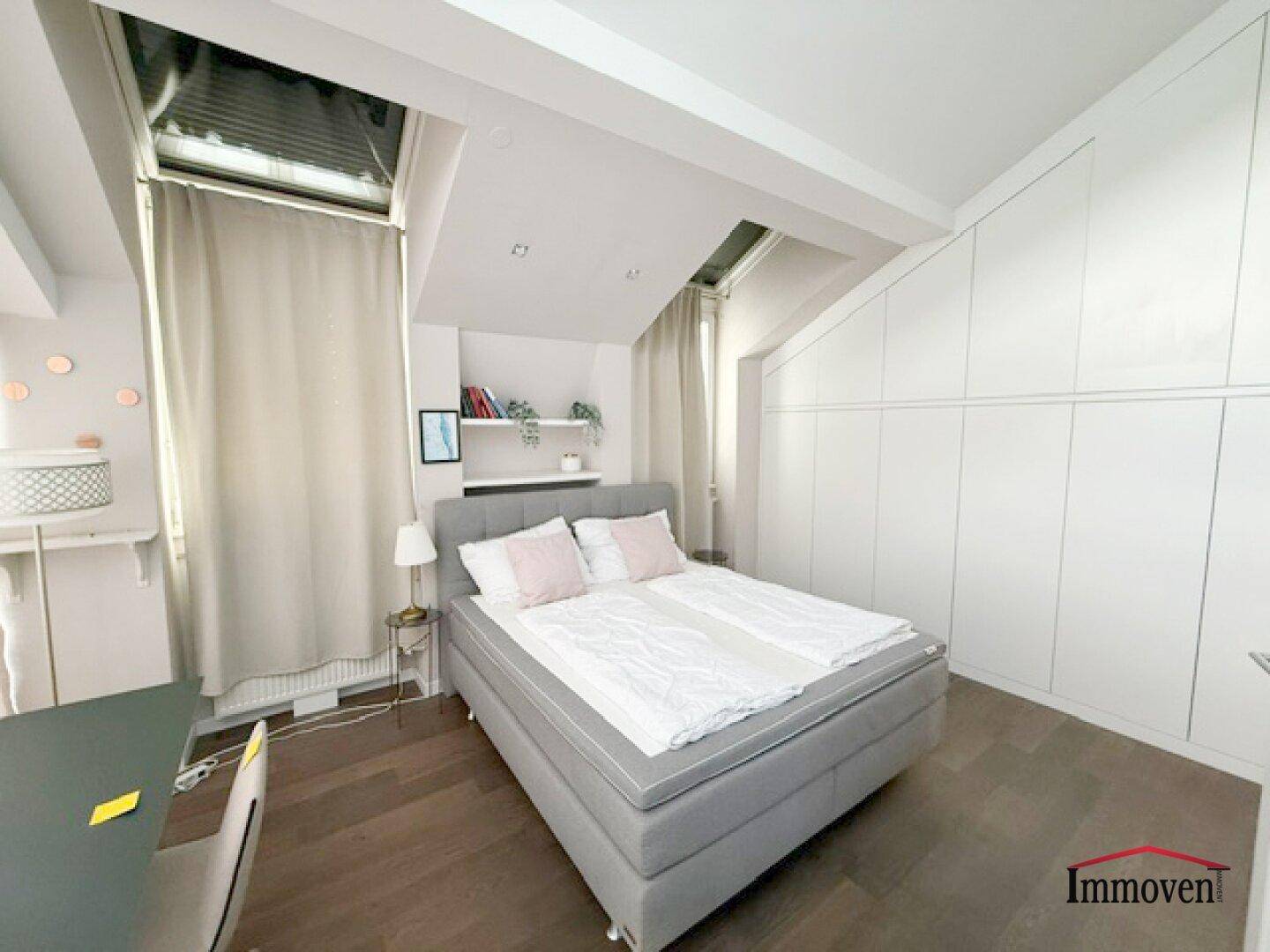 Geräumiges Schlafzimmer mit Einbauschränken, Holzboden und viel Tageslicht.