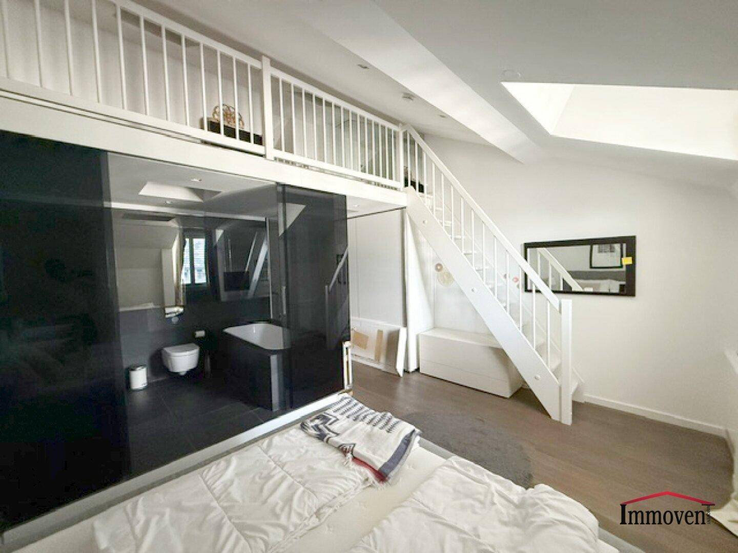 Schlafzimmer mit offener Galerie, Holzboden und integriertem Badezimmer.