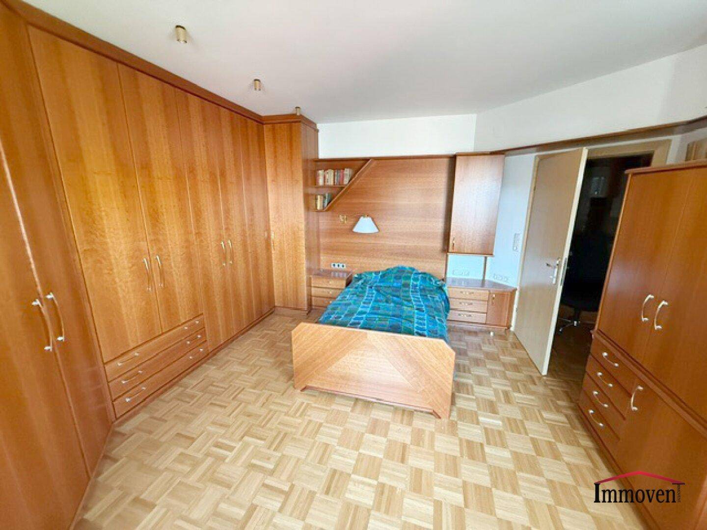Schlafzimmer mit umfangreichen Holzschränken, Parkettboden und integriertem Bett.