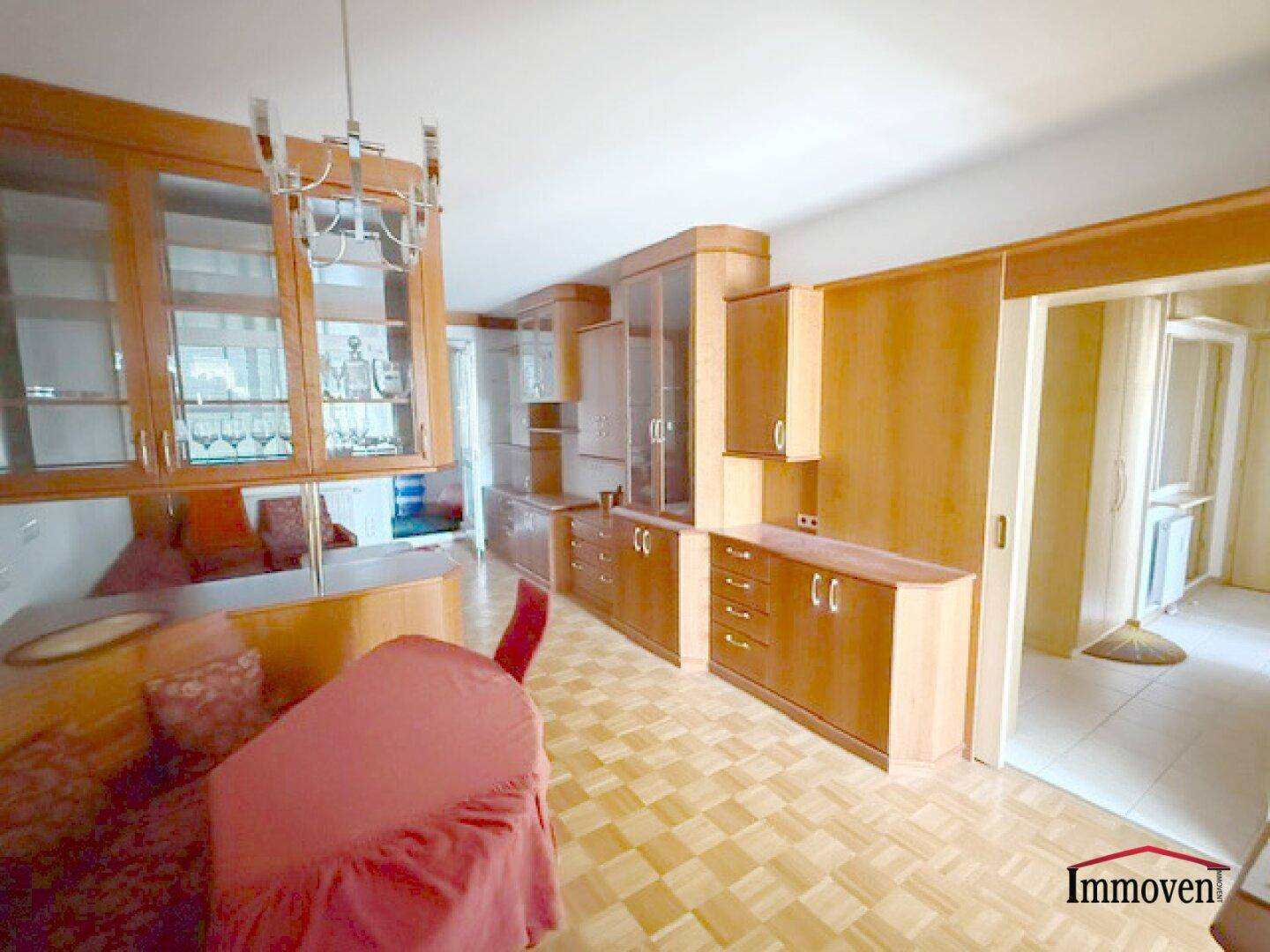 Helles Wohnzimmer mit Holzvertäfelung, Parkettboden und integrierten Schränken.