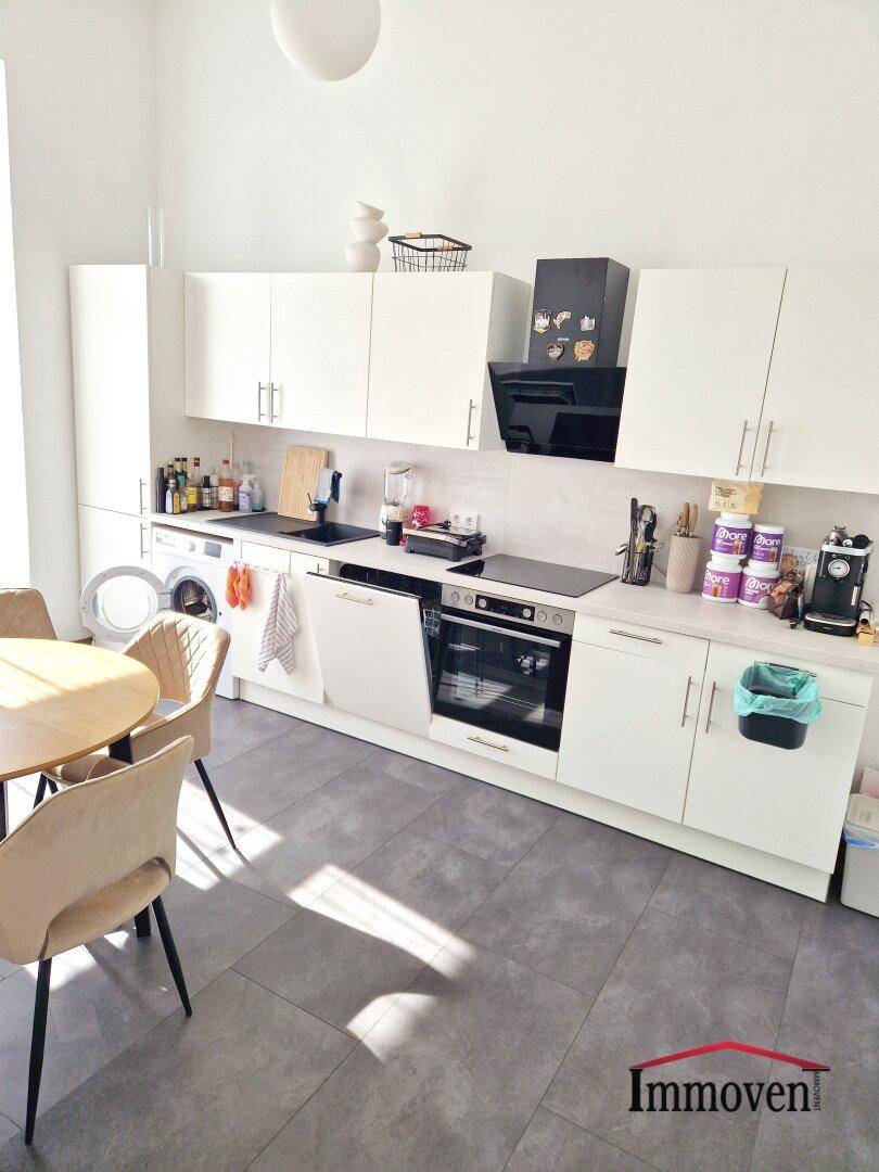Moderne weiße Küche mit integrierten Geräten, Essbereich und Waschmaschine.