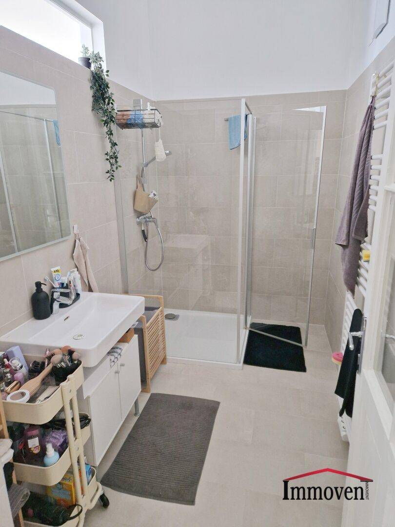 Modernes Badezimmer mit Duschkabine, Einzelwaschbecken und beheiztem Handtuchhalter.