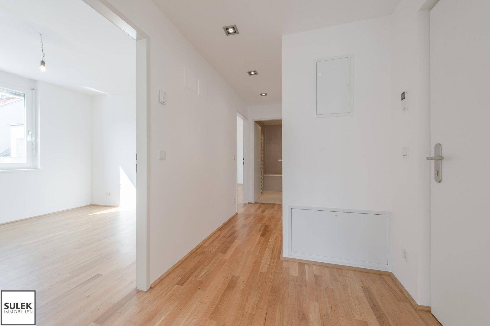 Geräumiger Flur mit Holzboden und modernen Einbaustrahlern, der die Räume verbindet.