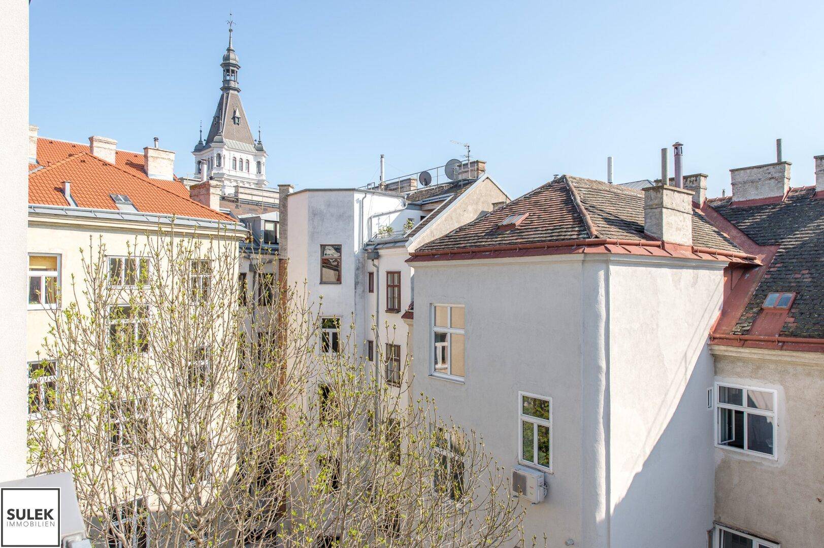 Panoramablick über die Dächer der Stadt mit historischen Gebäuden und einem Kirchturm.