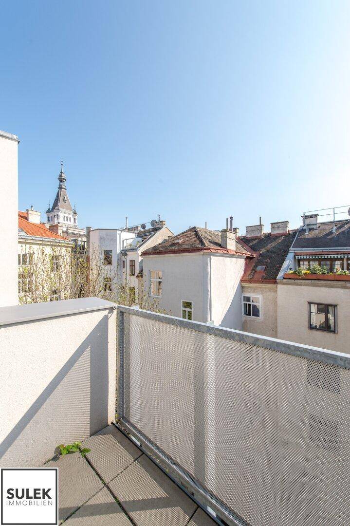 Kleiner Balkon mit Metallgeländer und weitem Blick über die Dächer der Stadt.
