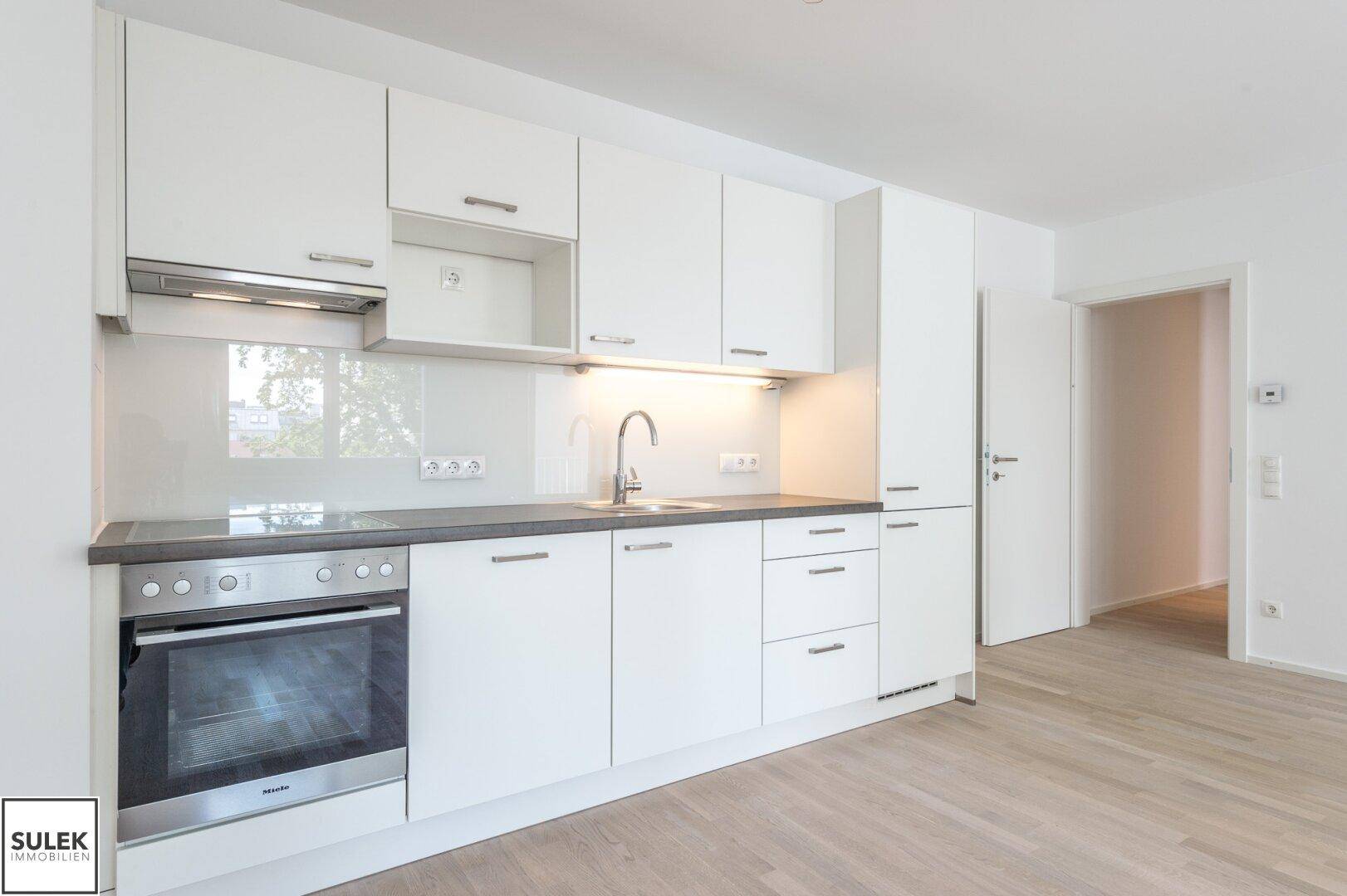 Helle Einbauküche mit weißen Fronten, Miele-Backofen und praktischer Arbeitsfläche.