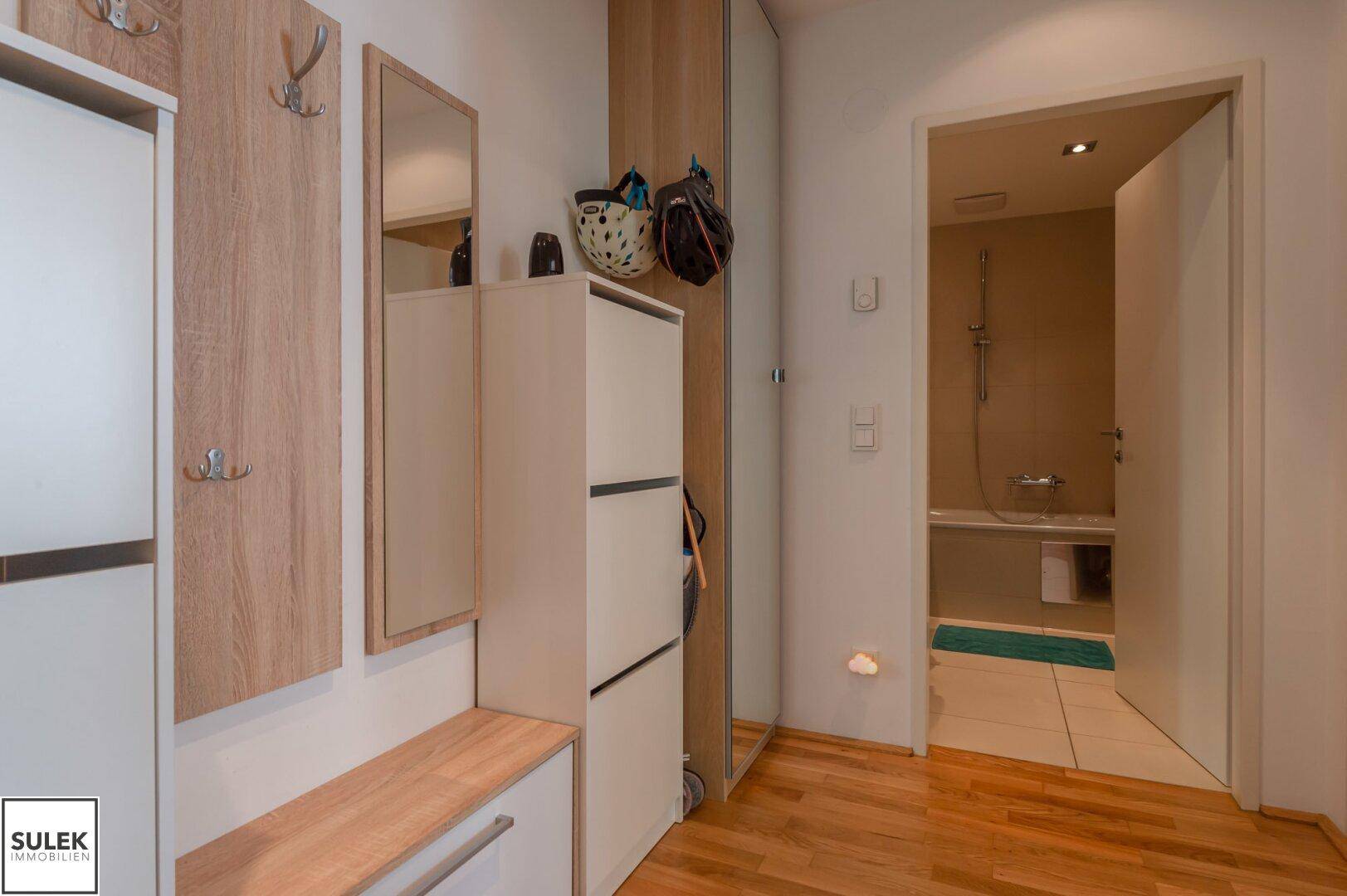 Heller Flur mit praktischen Schuhschränken und Garderobe, führt zum Badezimmer.