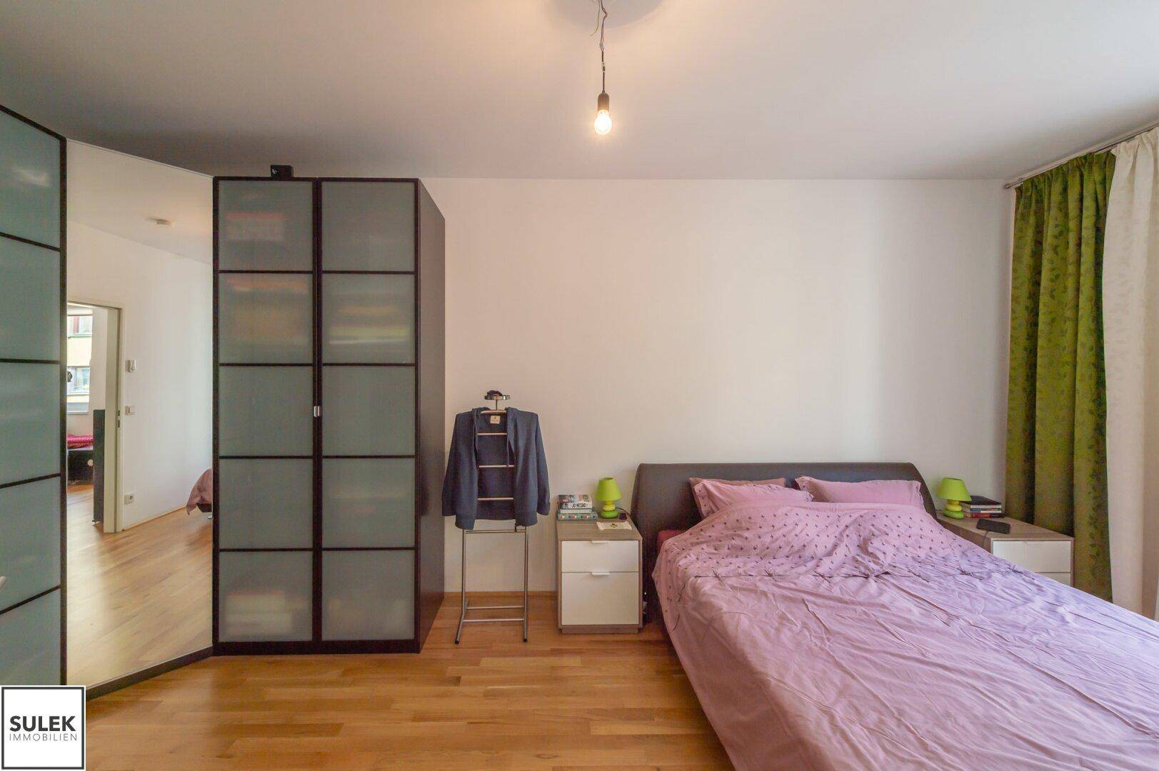 Schlafzimmer mit Doppelbett, Kleiderschrank und Holzboden, bietet eine ruhige Atmosphäre.